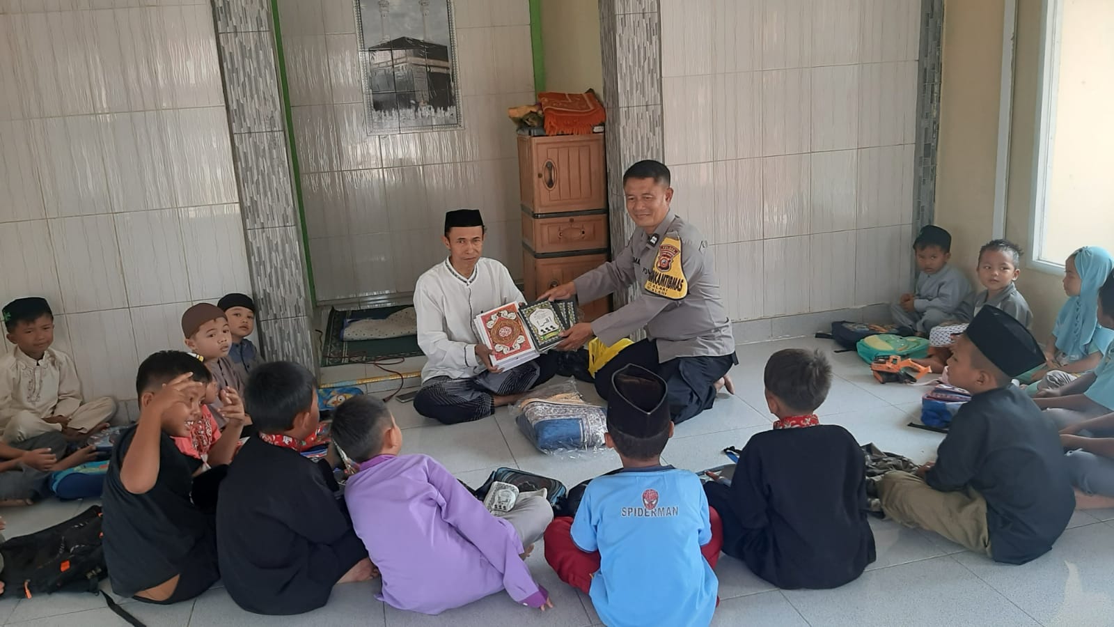 Bhabinkamtibmas Desa Klari Berikan Sarana Kontak Al-Qur’an dan Sejadah ke Pengajian Mushola Al Amanah