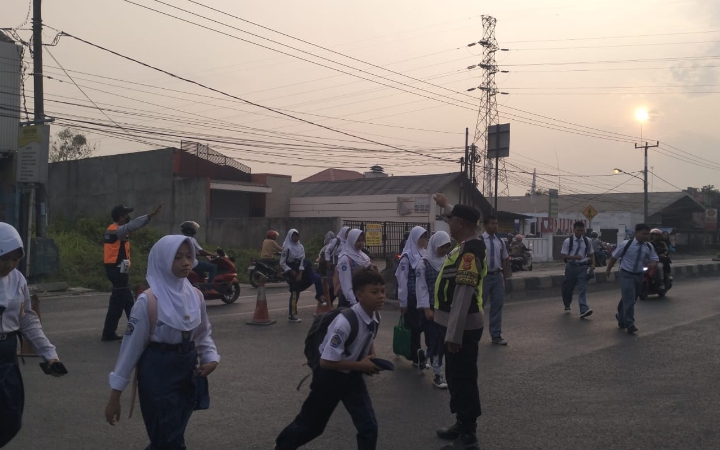 Sapa Pagi, Personel Polsek Klari Bantu Warga dan Pelajar Menyeberang di Jalan Raya Pantura Kosambi